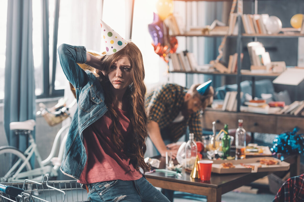 confused woman in birthday hat, man cleaning behind in messy room after party Post-Party Cleaning Service – Recover your Space without Effort! ππ§Ή